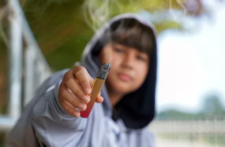 Jeune tend une cigarette électronique 