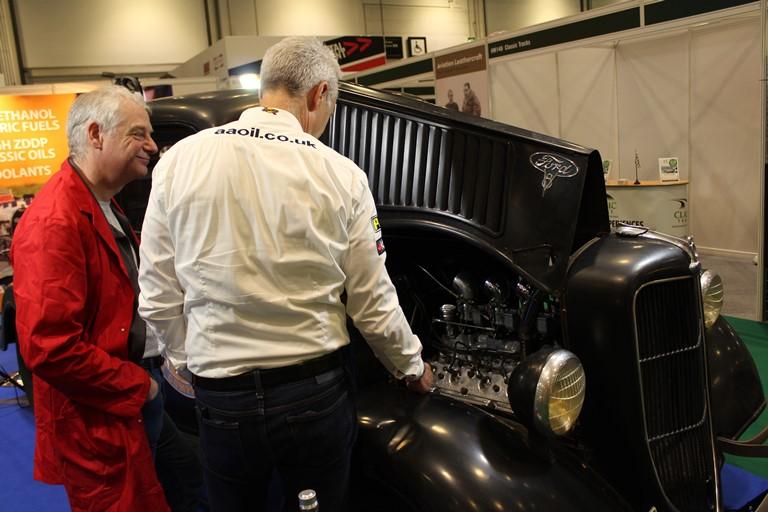 Exposant montrant le moteur d'une ancienne voiture à un visiteur du London Classic Car Show