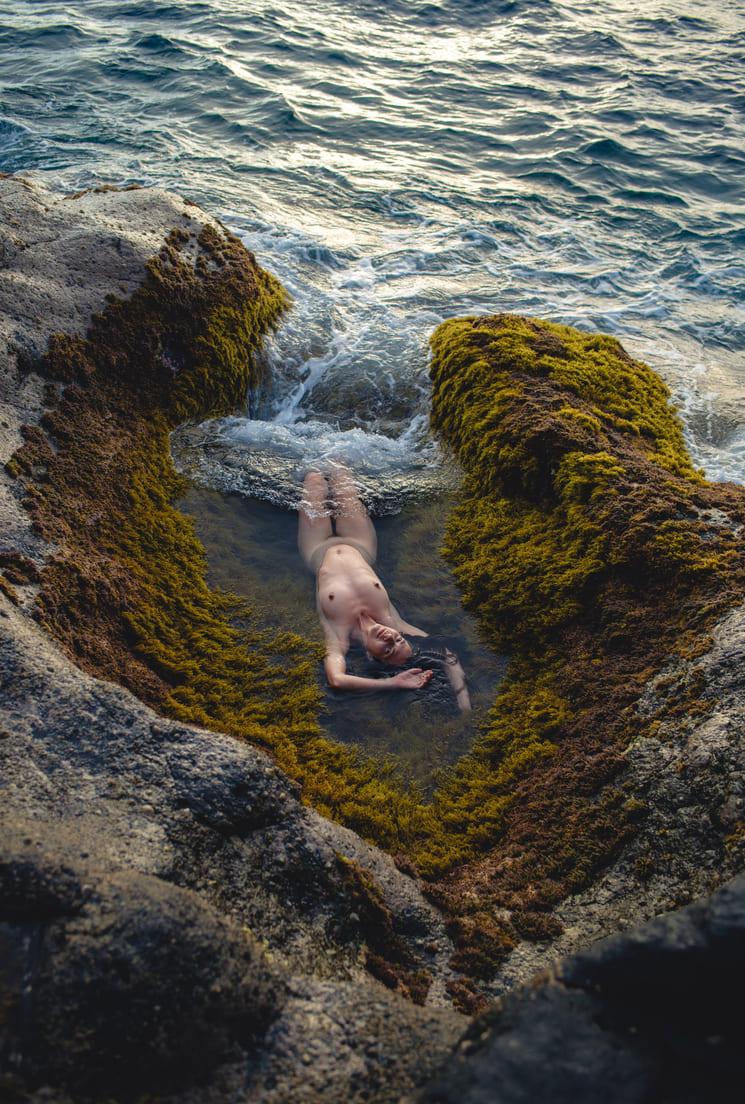 Femme nue flottant au milieu des rochers