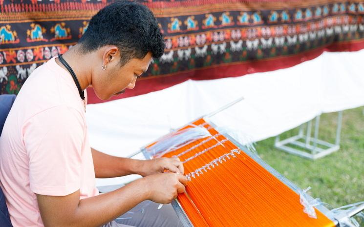 Un tisserand thailandais travaille sur un sarong en soie de Surin comportant des motifs du Petit Prince