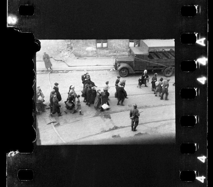 Juifs conduits à l’Umschlagplatz ; photo prise d’une fenêtre de l’hôpital St Zofia, à l’angle des rues Żelazna et Nowolipie, donnant très probablement (à confirmer) sur la rue Nowolipie ; commentaire de l’auteur noté après la guerre au dos du tirage conservé dans les archives de l’USHMM à Washington, D.C. : « Scènes de l’évacuation du ghetto, vers le 20 avril 1943 »