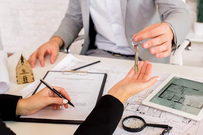 homme donnant des clefs à une femme pour l'achat d'un bien immobilier via une SCI française