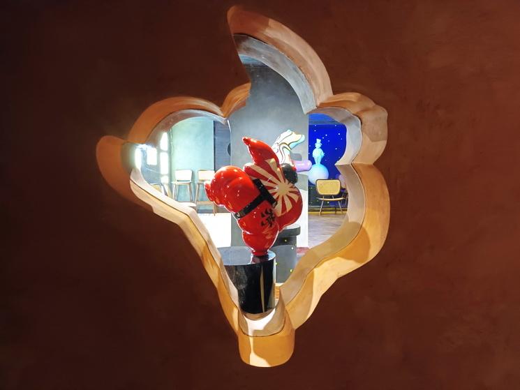 Vue d'une sculpture de sumo a travers une niche dans la galerie Envol d'Arnaud Nazare-Aga