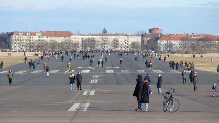Le Tempelhofer Feld sous le soleil avec de nombreux visiteurs qui se promènent, font fu vélo et du roller.
