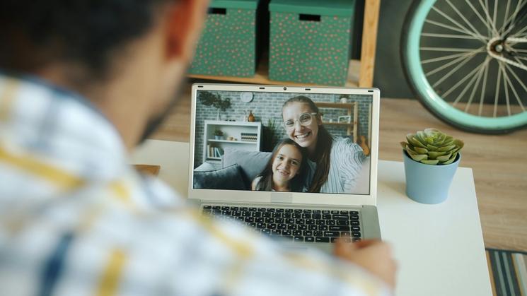 homme appel vidéo sa femme et sa fille sur ordinateur chemise carreaux 