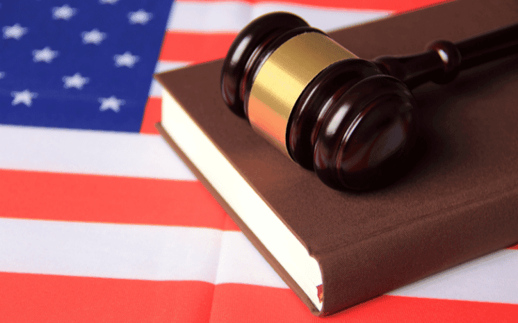 Un drapeau des Etats-Unis avec un marteau de juge posé dessus, où les avocats étrangers doivent retourner à l'université pour exercer 