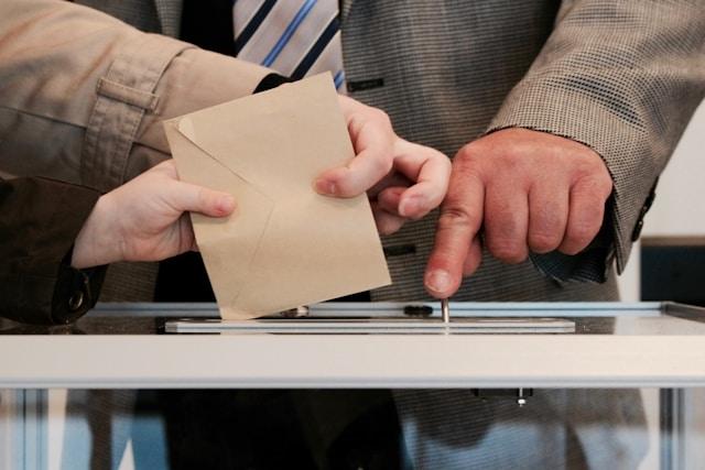 Deux personnes, un adulte et un enfant, déposent une enveloppe dans une urne lors d'un vote