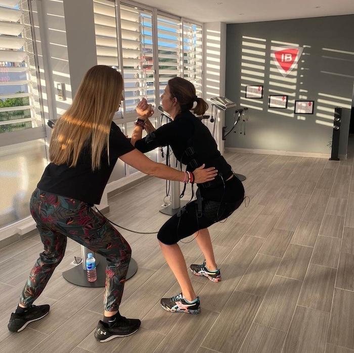 femme de dos en train de faire une séance d'électrostimulation EMS aidée par une coach dans le studio Iron BodyFit d'Alicante