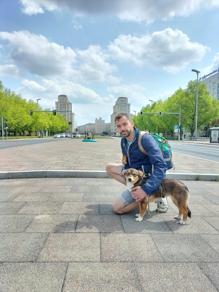 Un homme accroupi dans la rue avec un chien dans les bras.