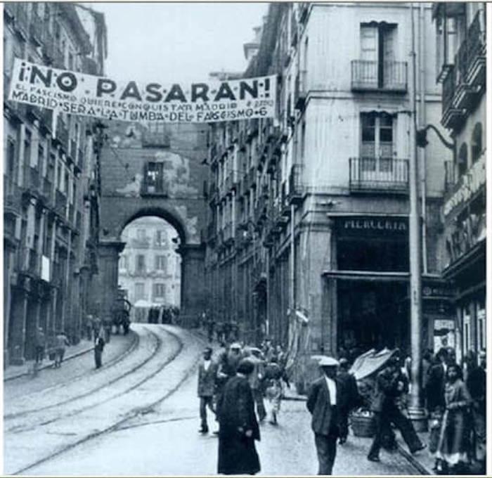 une photo en noir et blanc d'une rue de Madrid avec une banderolle "no pasaran" pendant la guerre civile