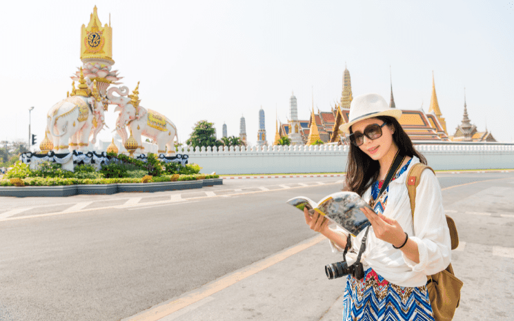 Une femme en train de lire son guide voyage devant un monument