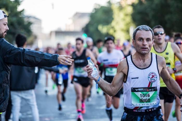 un coureur de marathon en train de donner une bouteille d'eau