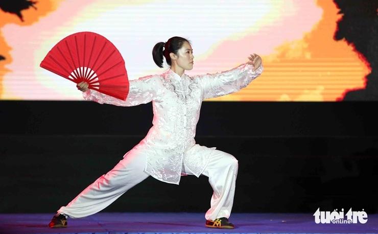 Une membre de la délégation chinoise de Wushu montre aux spectateurs son entraînement d'éventail lors de la cérémonie d‘ouverture du festival international d’art martial d’Ho Chi Minh Ville le 21 novembre 2025.