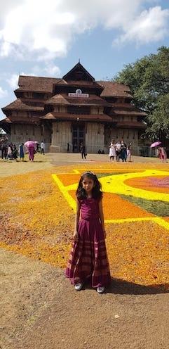 Une petite fille habillée pour Onam devant un temple dans le Kerala