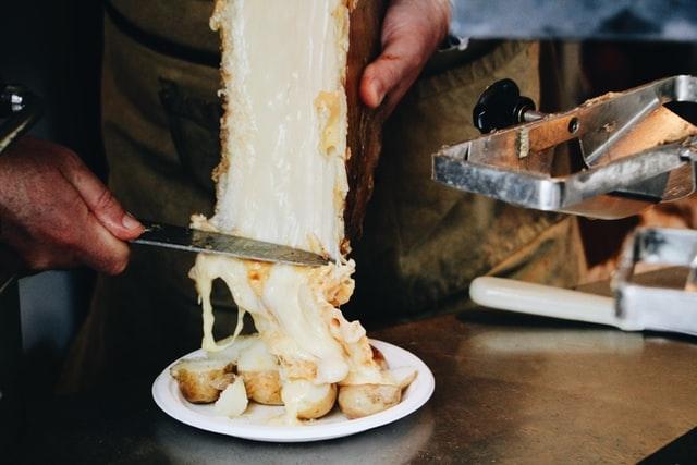 une main avec un couteau en train de couper du fromage