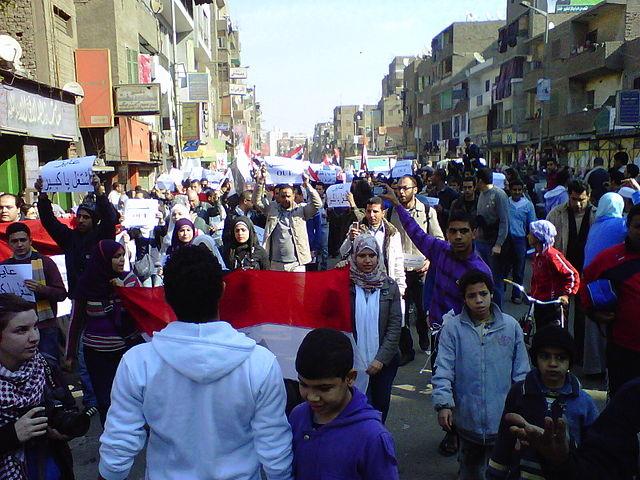 des manifestants dans les rues du Caire en janvier 2011 avec des drapeaux et des banderoles