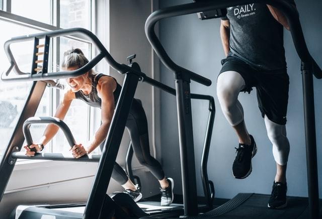 un homme et une femme sur des machines dans une salle de sport