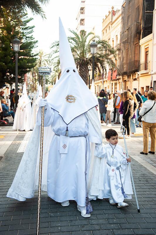 Confrérie du Saint-Sépulcre avec sa cagoule et son fils lui tenant la main