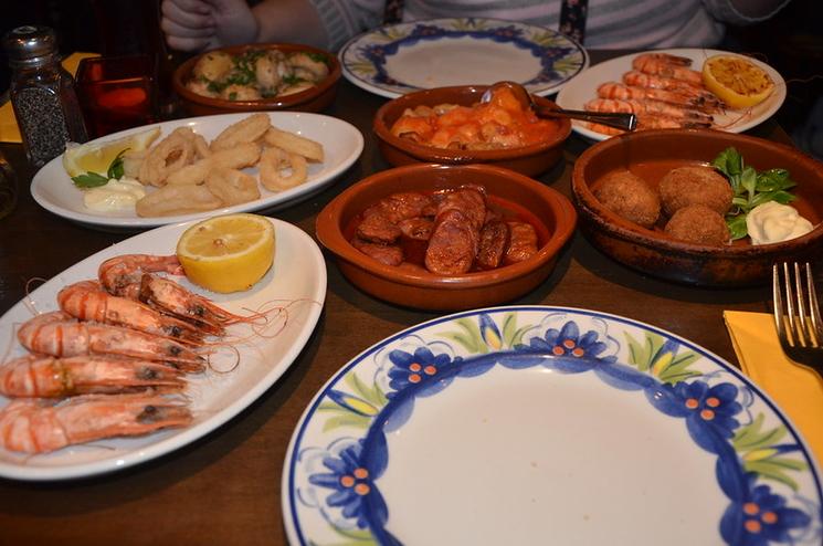 des assiettes avec des crevettes, du chorizo, des croquettes et des calamars