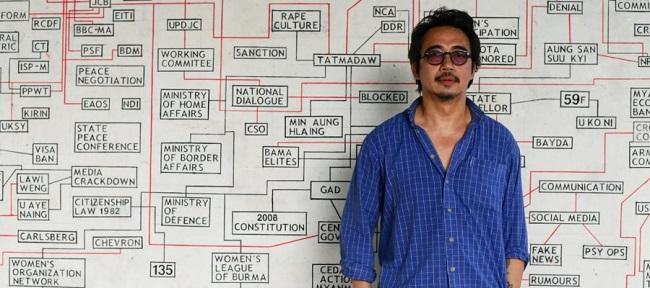 Sawangwongse Yawnghwe devant son œuvre intitulée « Le complexe industriel de la paix en Birmanie »