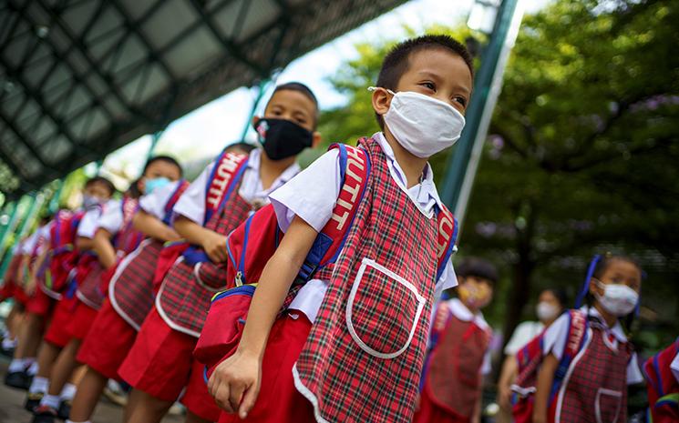 Des élèves thaïlandais masqués en rang à l'école
