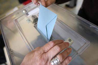 une personne dépose son bulletin de vote dans l'urne