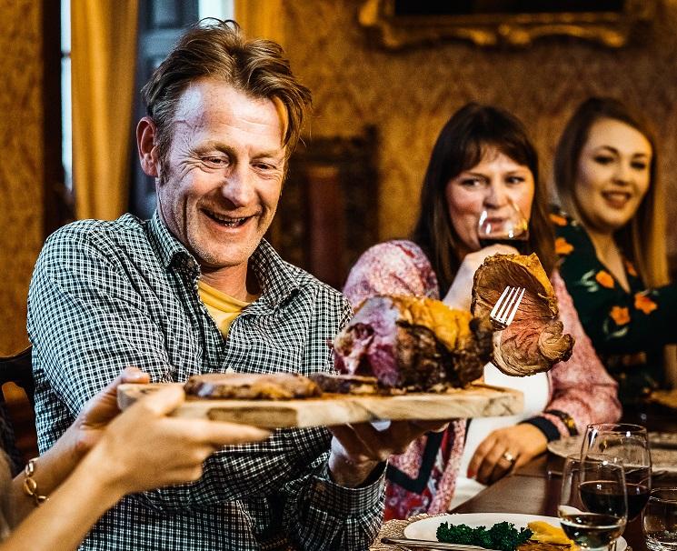 Des anglais attablés, tout sourire, se font passer le rôti