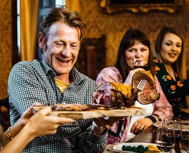 Des anglais attablés, tout sourire, se font passer le rôti