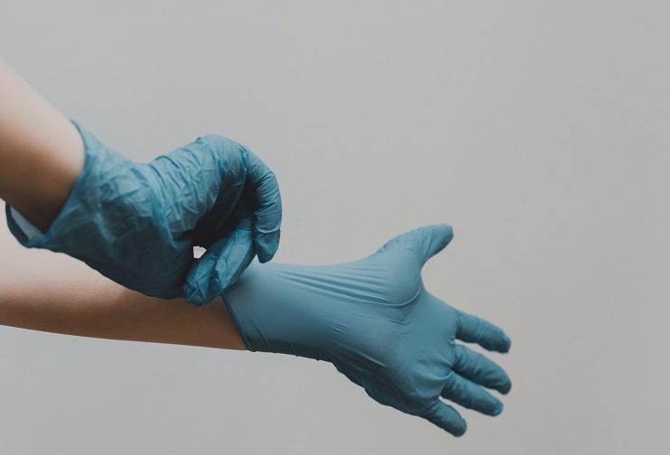 une personne enfile des gants chirurgicaux