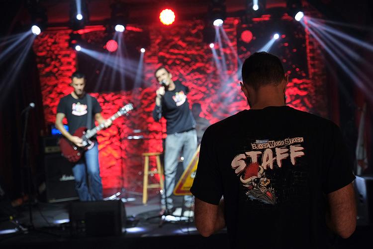 Un personne du Staff du Blackwoodstock Festival devant la scène de Music Station où joue un groupe de musique