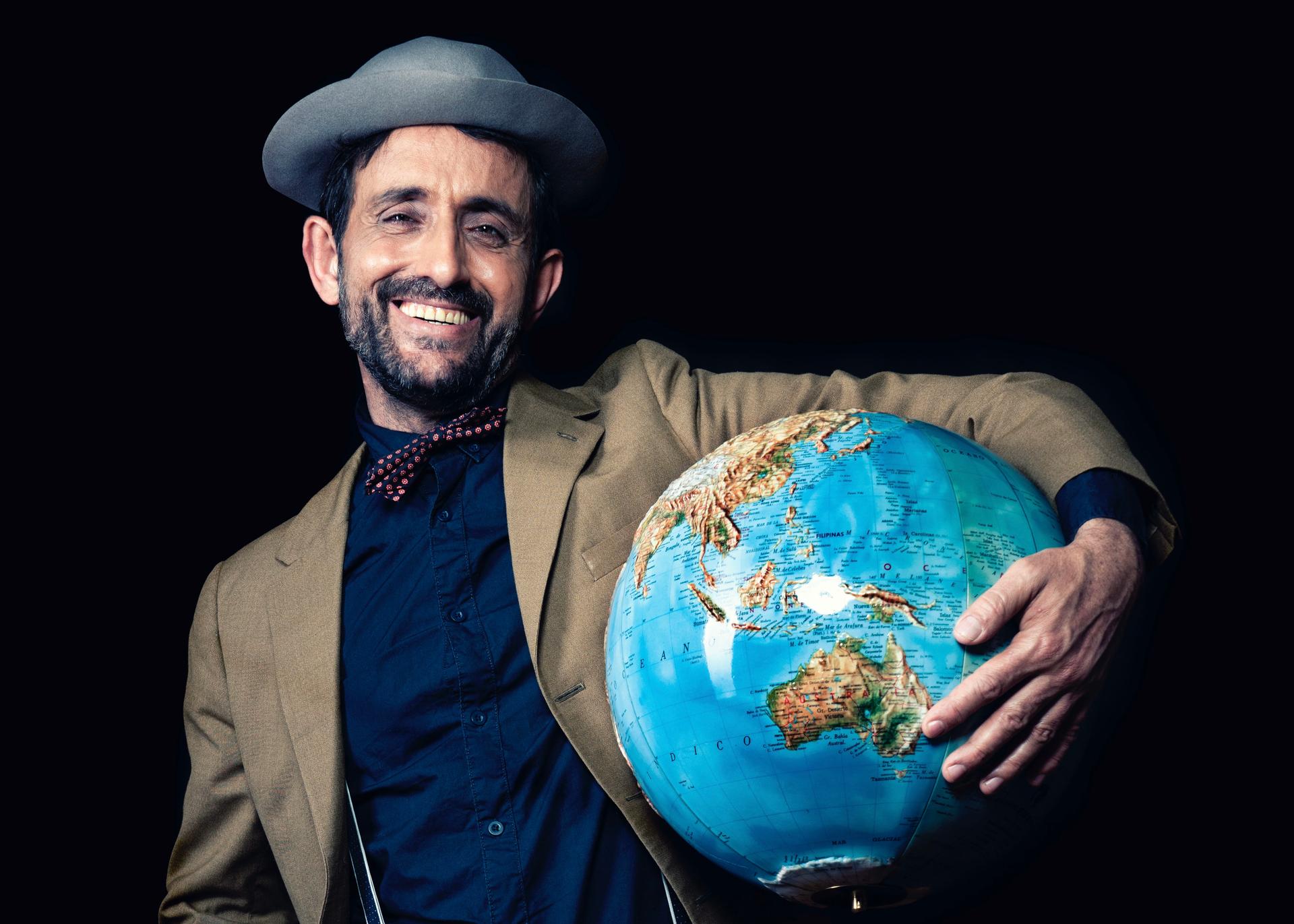 Un homme avec un chapeau qui tient un globe terrestre dans ses bras