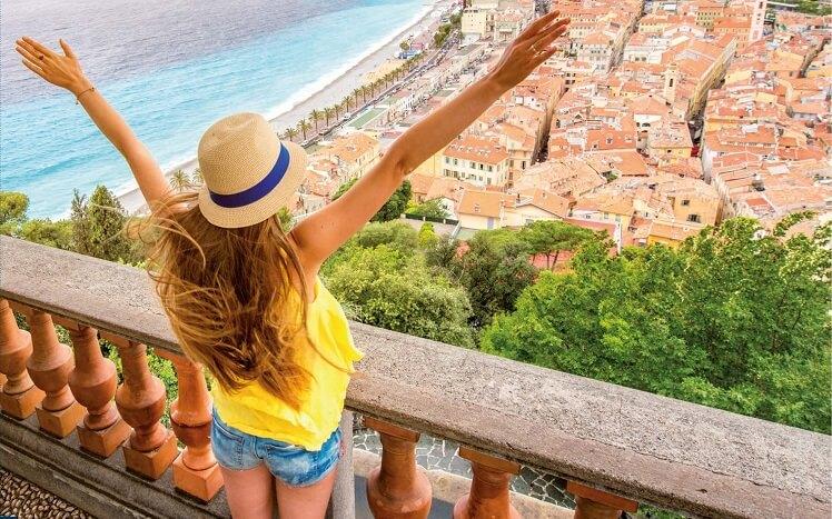 une femme avec chapeau bras levé devant mer