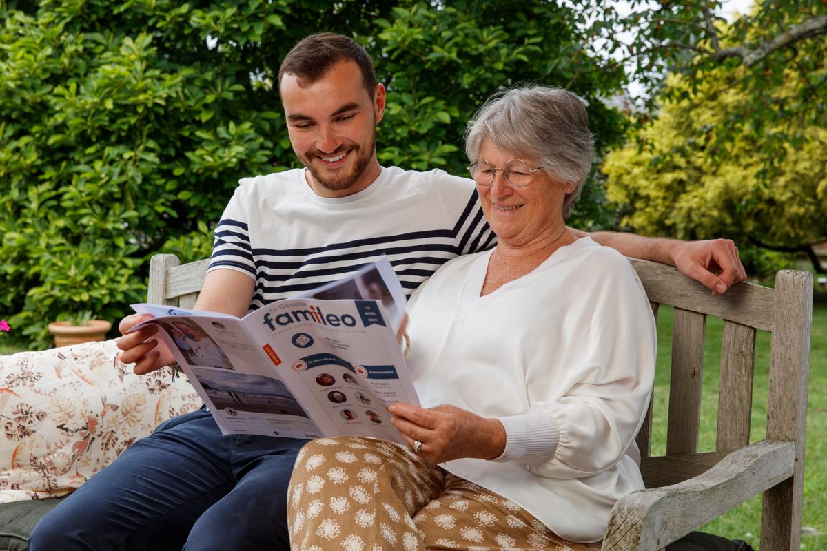 un homme et une femme en train de lire un magazine assis sur un banc