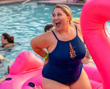 Une femme dans une piscine, sur une grande bouée, souriant largement