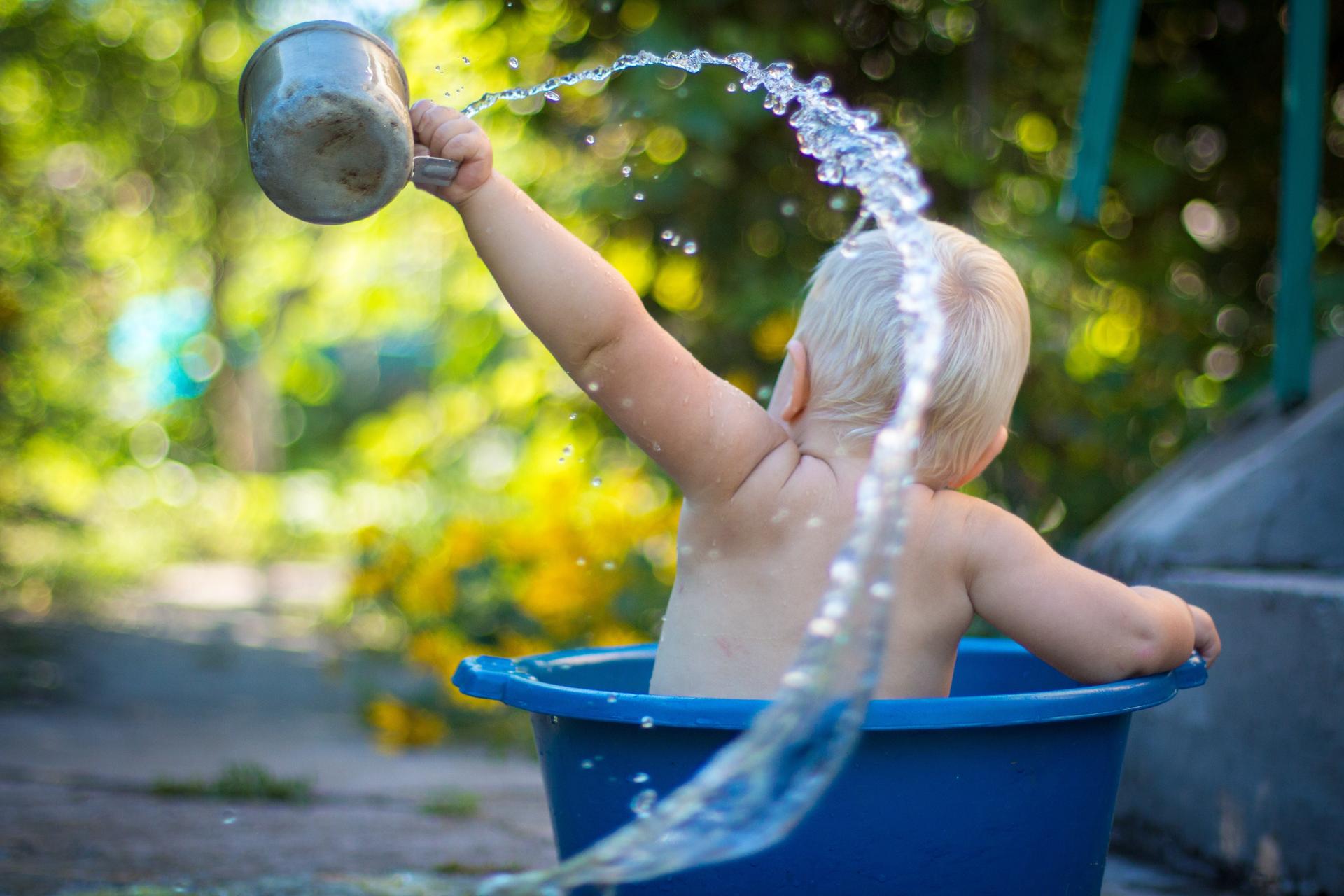 Enfant dans une bassine qui s’arrose