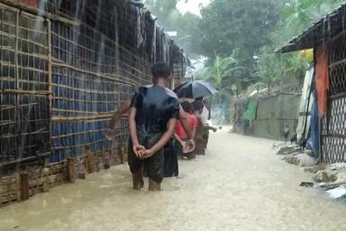 Des hommes marchent dans un camps de réfugiés inondé (DR)