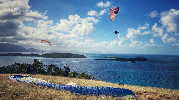 Trois personnes sautent en parapente du haut de la colline du Parc de Ouen Toro à Nouméa en Nouvelle-Calédonie