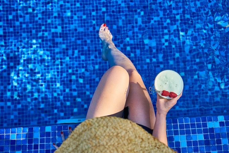 Une femme les pieds dans l'eau d'une piscine bleue