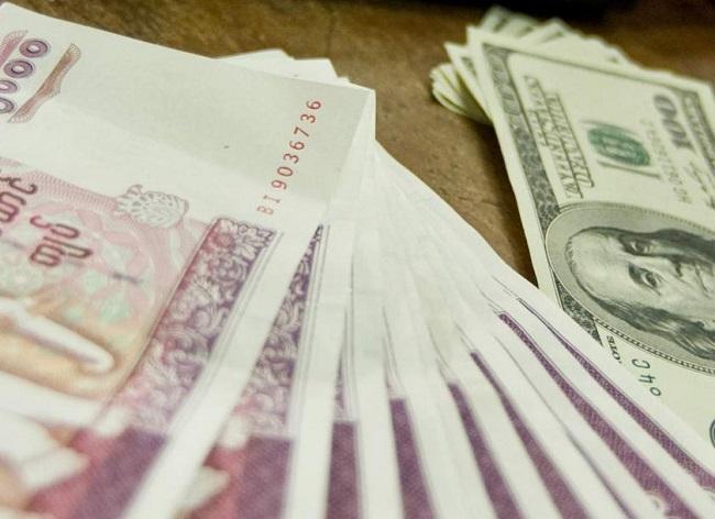 Des billets rouges de 5 000 kyats et de dollars côte à côte