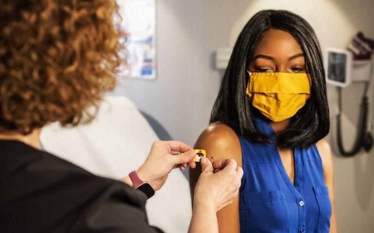Une jeune femme avec un masque se faisant vacciner contre le COVID-19