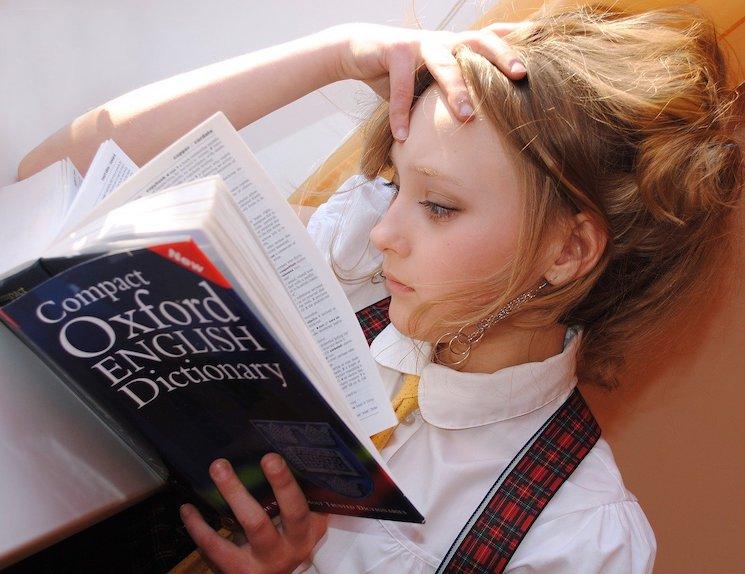 Une fille lisant attentivement le dictionnaire Oxford en anglais