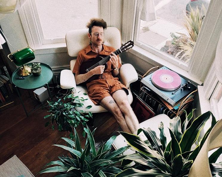 un homme joue du ukulélé dans un fauteuil