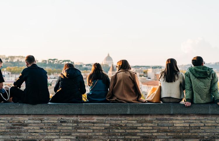 Des trentenaires assis sur un muret à Rome