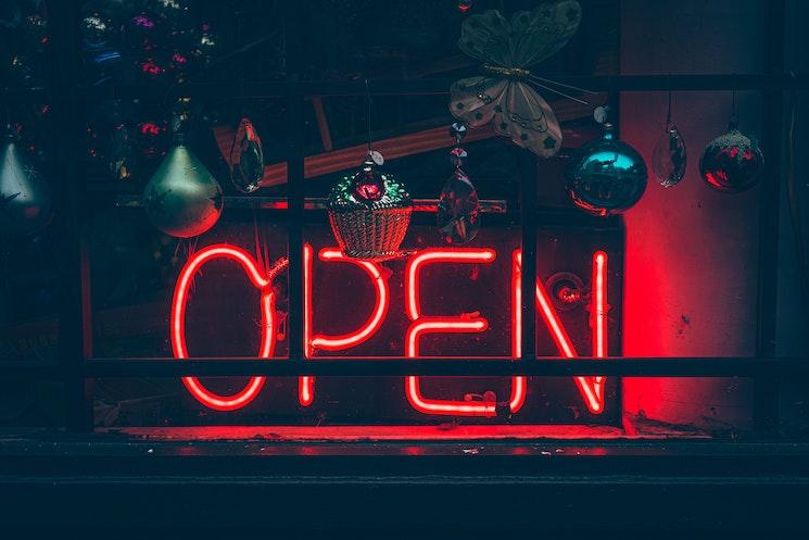 Un panneau rouge qui annonce que la boutique est ouverte acec déco de Noël