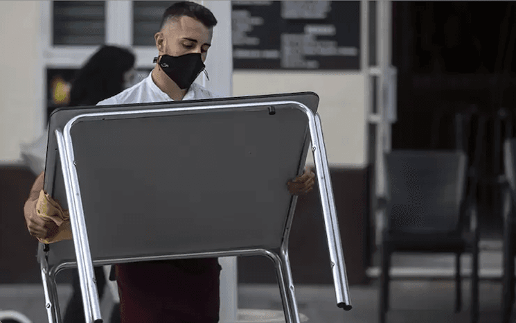 un serveur désinfecte une table contre le covid en andalousie