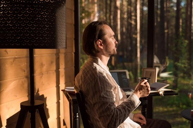 Une personne tenant un tasse et profitant du soleil chez elle