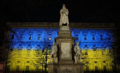 statue de leonardo da vinci et bâtiment illuminé en jaune et bleu