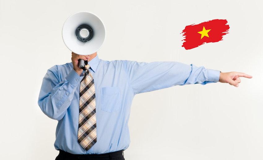 Une personne avec un mégaphone et un drapeau du vietnam dans le coin de l'image