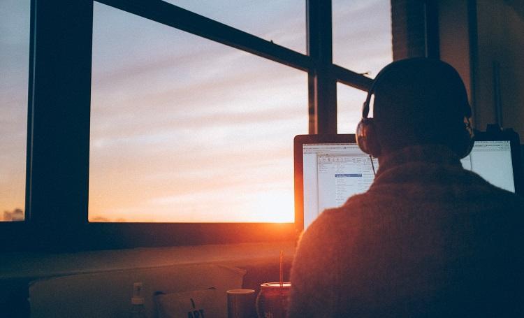 un homme télétravaille sur ordinateur avec lever de soleil simon-abrams-unsplash