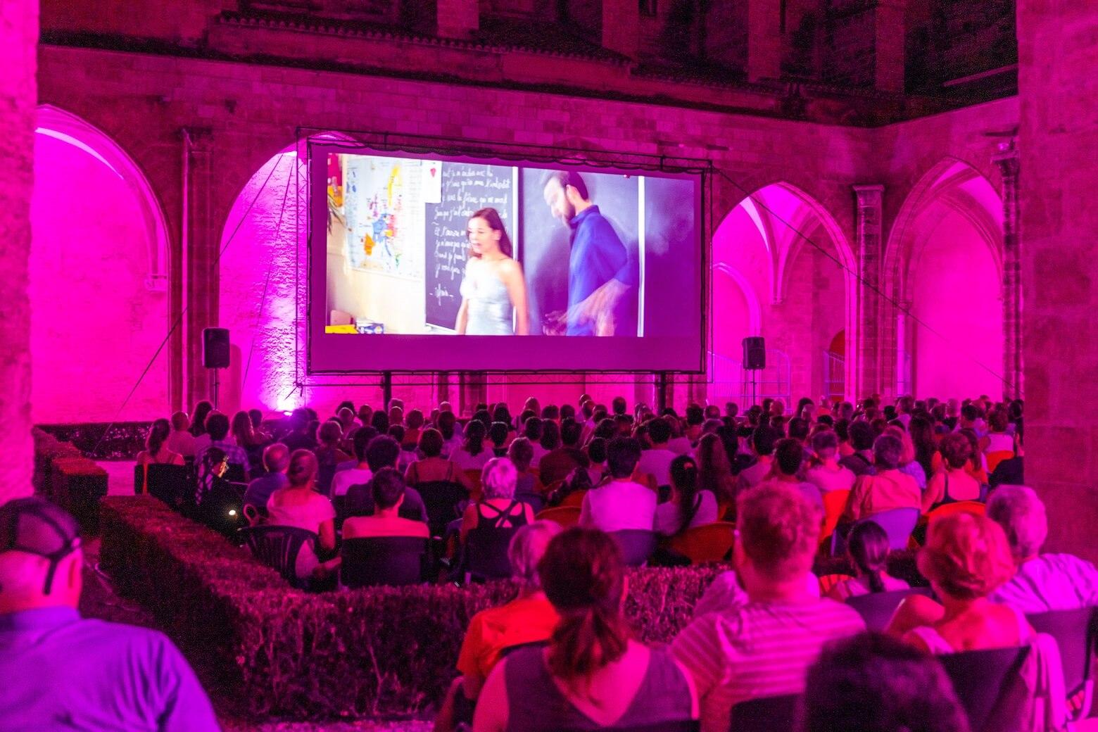 une projection de film sur grand écran entouré de lumière violette au centre del carme
